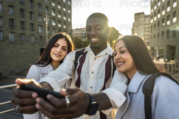 Diverse group of young friends is smiling and laughing together while taking a selfie with a
