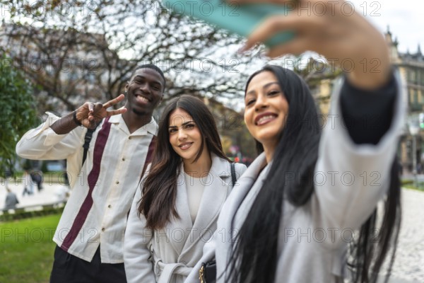 Happy diverse friends smiling and posing for a cheerful selfie with a smartphone outdoors in a city