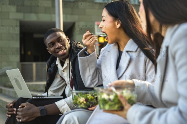 Multi ethnic young professionals enjoying a healthy salad for lunch during a break, sitting