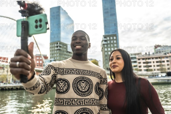 Smiling diverse couple creating content for social media, capturing a selfie video with a