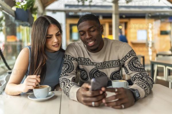 Young diverse couple enjoying a moment together at a cafe, discussing content on a smartphone and