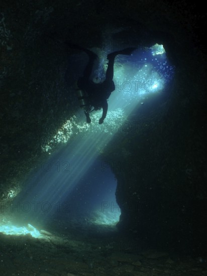 A dark cave is explored by a diver who is surrounded by dramatic rays of light. Fraskeric dive