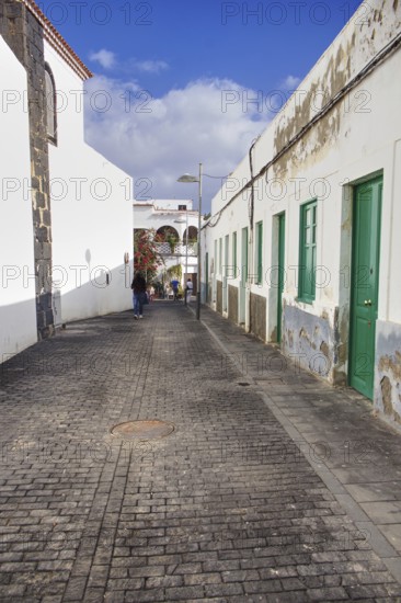 Narrow cobblestone street in Arrecife, Lanzarote, in portrait mode. On the left the back of the