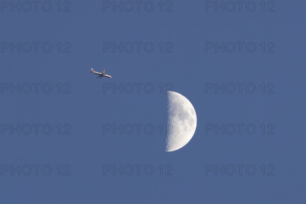 Airbus commercial passenger airliner jet aircraft of British airways in flight with the moon in the