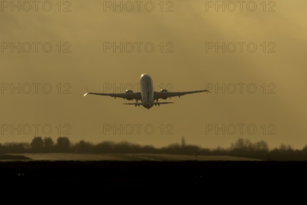Airbus commercial passenger airliner jet aircraft taking off in flight silhouette at sunset at