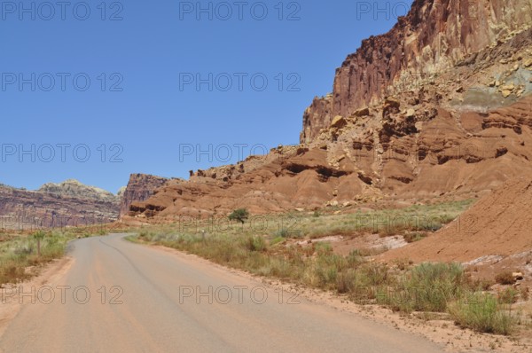 Deserted road through a wild red rock landscape under blue sky, Capitol Reef National Park, Utha,