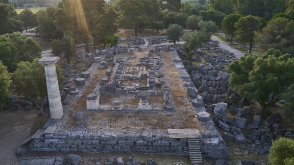 Temple of Zeus in backlight, ancient ruins surrounded by trees, with a stone column and
