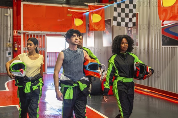 Diverse friends preparing for a go kart race, holding helmets and wearing race suits, walking