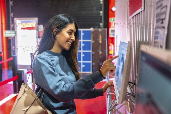 Young woman smiling while interacting with a touchscreen display, checking in for a karting