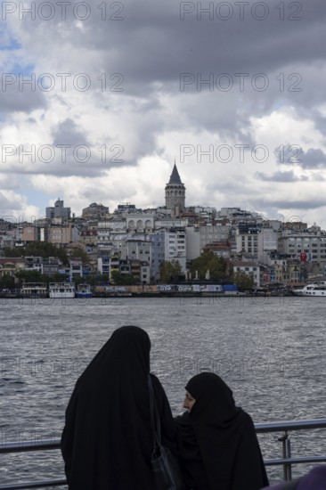 Istanbul, Turkey. September 18th 2025. Muslim women beside the Golden Horn with the Galata Tower