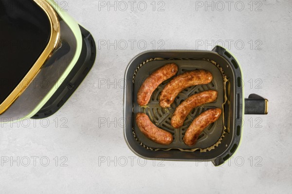 Natural casing sausages in an air fryer, being cooked at high heat. This activity shows the process