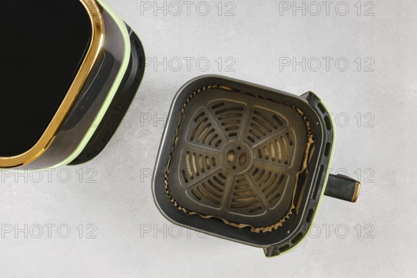 Top view of modern air fryer with empty basket lined with parchment paper, ready for quick healthy