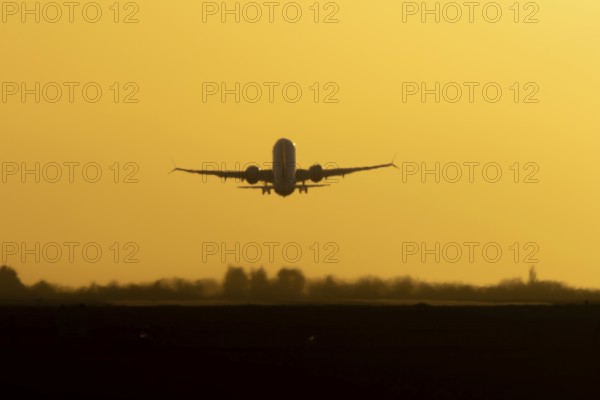 Airbus commercial passenger airliner jet aircraft taking off in flight silhouette at sunset at