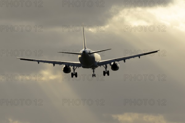Commercial passenger airliner jet aircraft in flight on approach to land at sunset at London
