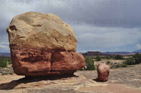 Large round boulder in an open desert landscape under a cloudy sky, Canyonlands National Park,