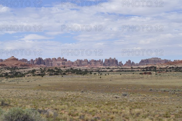 Wide desert landscape with distinctive rock structures under a slightly cloudy sky, Canyonlands