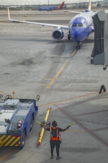 Phoenix, Arizona - A ground crew worker directs a Southwest Airlines jet as it arrives at Sky