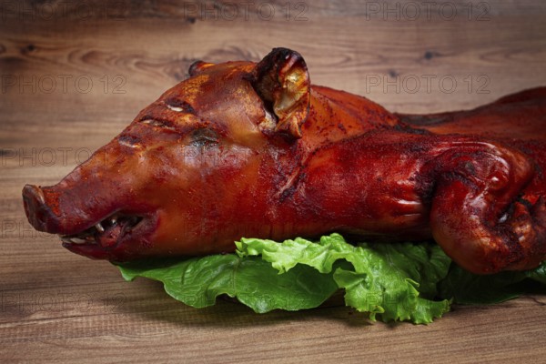 Baked, fried piglet, on a wooden table, no people, The whole piglet is baked and served on the