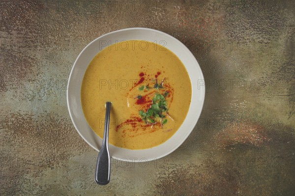 Pumpkin cream soup, in a white bowl on a textured background, top view, homemade, no people, rustic
