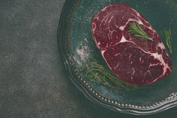 Steak made from fresh beef, with herbs and various spices, on a plate, ready to cook, there are no