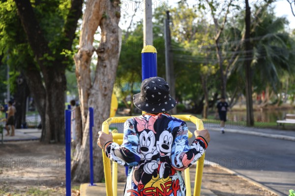 Bangkok, Thailand. March 4th 2025. An elderly lady uses the public outdoor gym exercise machines in