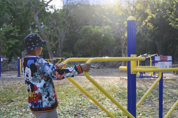 Bangkok, Thailand. March 4th 2025. An elderly lady uses the public outdoor gym exercise machines in