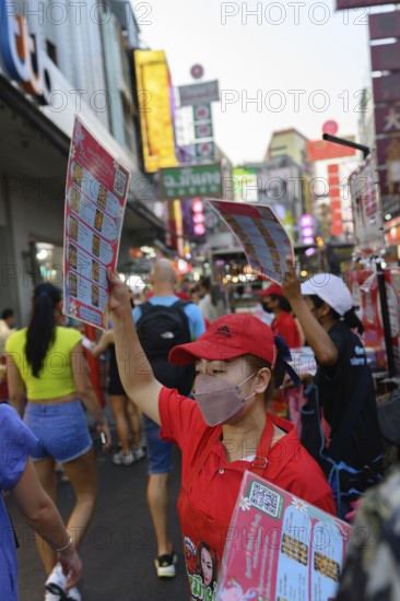 Bangkok, Thailand. February 18th 2025. Restaurant waitresses wave menus to attract customers in