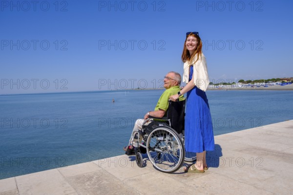 Senior in wheelchair looking at the sea, vacation with a handicap, Grado, Julian-Friuli, Adriatic