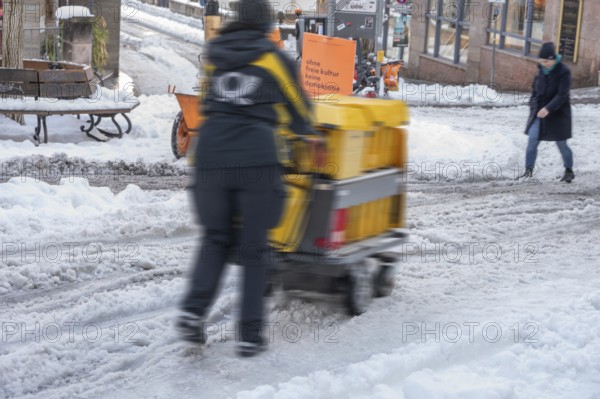 Movement, postman walking with loaded handcart on wintry roads in the city, Nuremberg, Middle