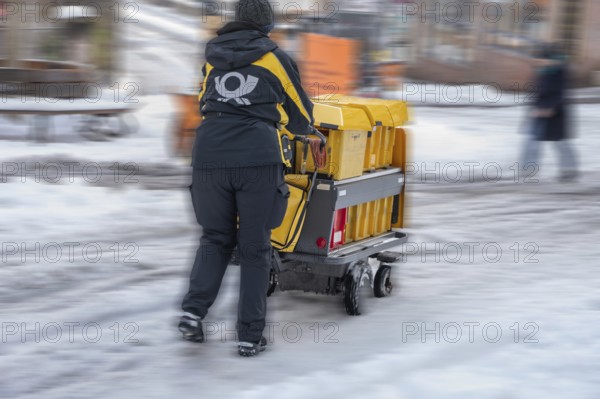 Movement, postman walking with loaded handcart on a wintry road in the city, Nuremberg, Middle