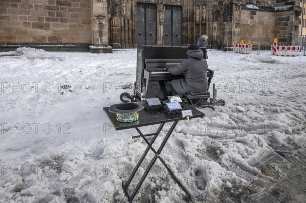 Musician playing a piano in the snow in front of St. Lorenz Church, Nuremberg, Middle Franconia,