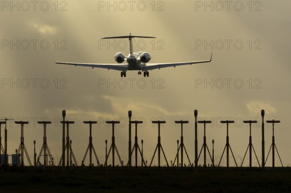 Executive business jet aircraft in flight on approach to land at sunset at London Stansted airport,