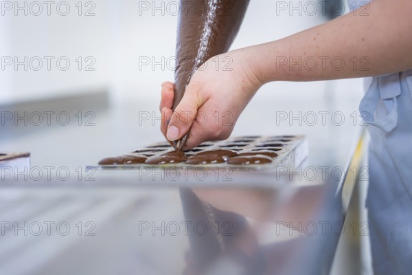 Chocolate is pressed into a chocolate mold by one hand, vegan chocolates production, Haselstaller