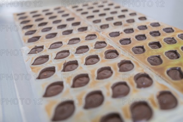 Close-up of chocolate molds with liquid chocolate on a table, vegan chocolates production,