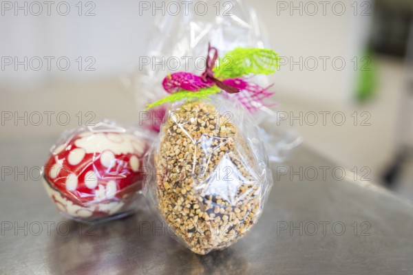 Gift wrapping of Easter eggs made from sweets and nuts in transparent foil, Easter production of