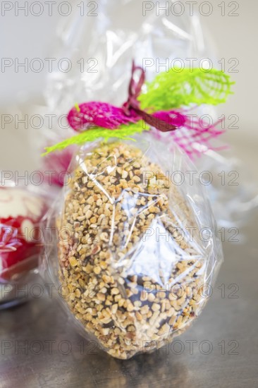 Chocolate decorated with colorful ribbon with nuts in cellophane, Easter production of regional