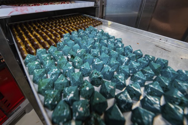 Blue geometric chocolates with shiny surface in rank and file, Easter production of regional