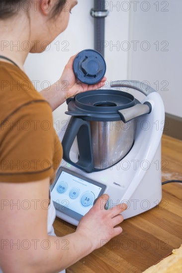 Person places the lid on a food processor during preparation, vegan cake production, Haselstaller