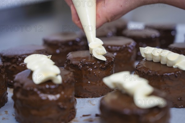 Some chocolate cakes are artfully decorated with cream from a piping bag, vegan cake production,
