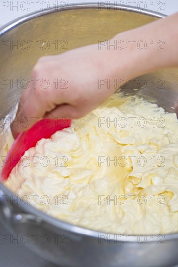 Hand stir buttercream in a metal bowl with a pink dough spatula, vegan cake production,