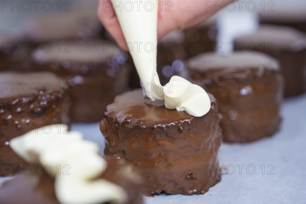 Several chocolate cakes are decorated with cream from a piping bag, Vegan Tart Production,
