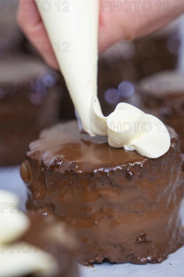 Hand decorated a chocolate cake with cream from a piping bag, vegan cake production, Haselstaller