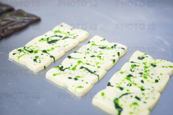 White chocolate bars with green patterns lying side by side on a table, vegan chocolate production,