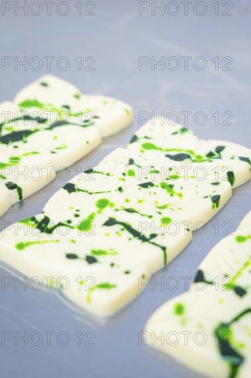 White chocolate bars with green splashes and patterns on a table, vegan chocolate production,