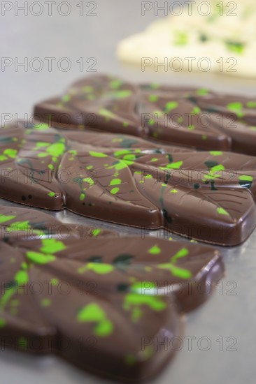 Close-up of dark chocolate bars with green patterns on a table, vegan chocolate production,