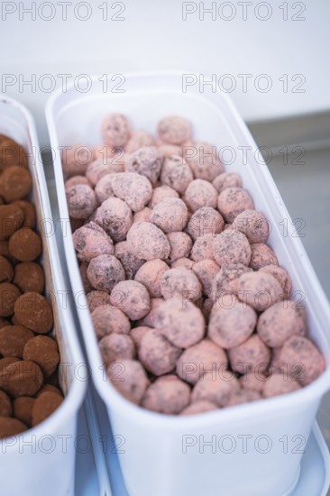 A container full of pink chocolates in a kitchen, chocolate quail eggs, Easter production,
