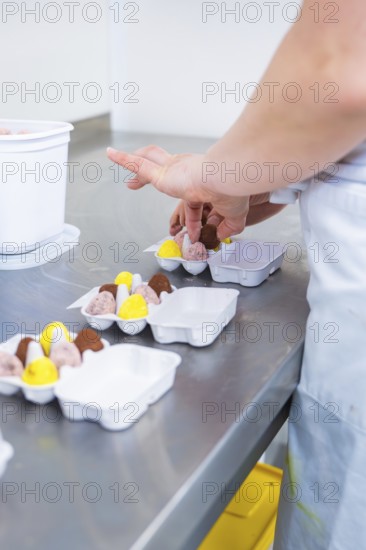 A person wraps chocolates in a package in a kitchen, chocolate quail eggs, Easter production,