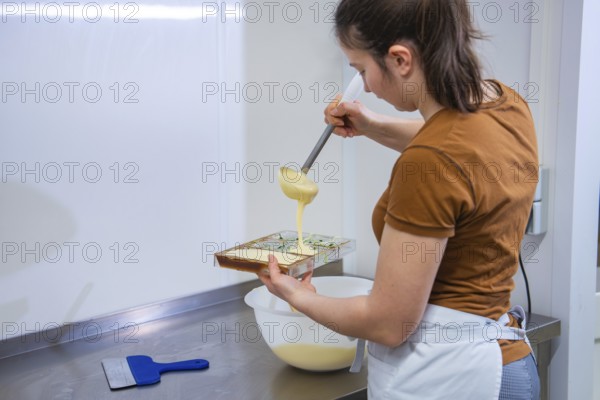 A woman pours chocolate mix into a mold in a kitchen, chocolate quail eggs, Easter production,
