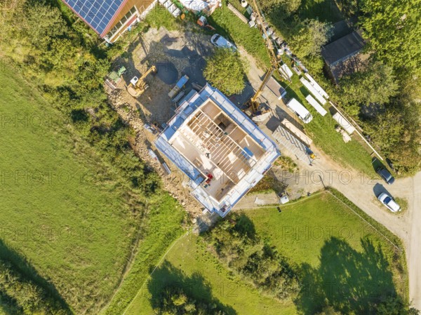 Aerial view of a construction site with grassy areas and an assembled house under construction,