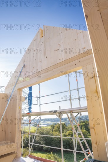 Timber building under construction with scaffolding and views of the landscape under blue sky,